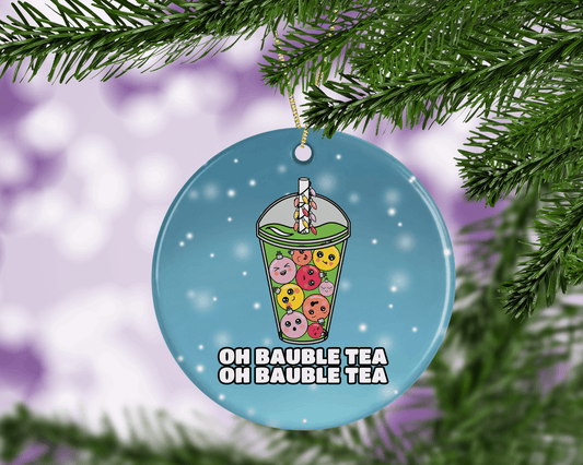 A round ceramic Christmas decoration to hang from a tree. Has a hand drawn illustration of boba bubble tea with baubles instead of tapioca bubbles.