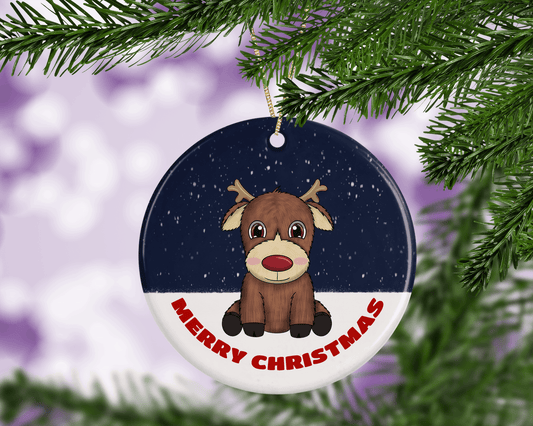 A round ceramic Christmas decoration to hang from a tree. Has a hand drawn illustration of a cute red nosed reindeer sitting in the snow.
