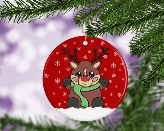 A round ceramic Christmas decoration to hang from a tree. Has a hand drawn illustration of a cute red nosed reindeer with a red snowy background.