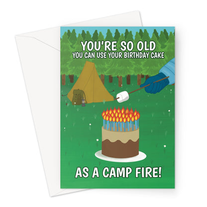 Funny birthday card showing a birthday cake with lots of candles used as a campfire. Person roasting marshmallow next to tent. Text reads “You’re so old you can use your birthday cake as a campfire.”