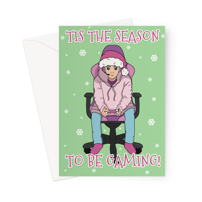 Funny gamer Christmas card featuring a person in a pink hoodie and Santa hat playing video games on a green background with snowflakes and the text “’Tis the Season to Be Gaming!”