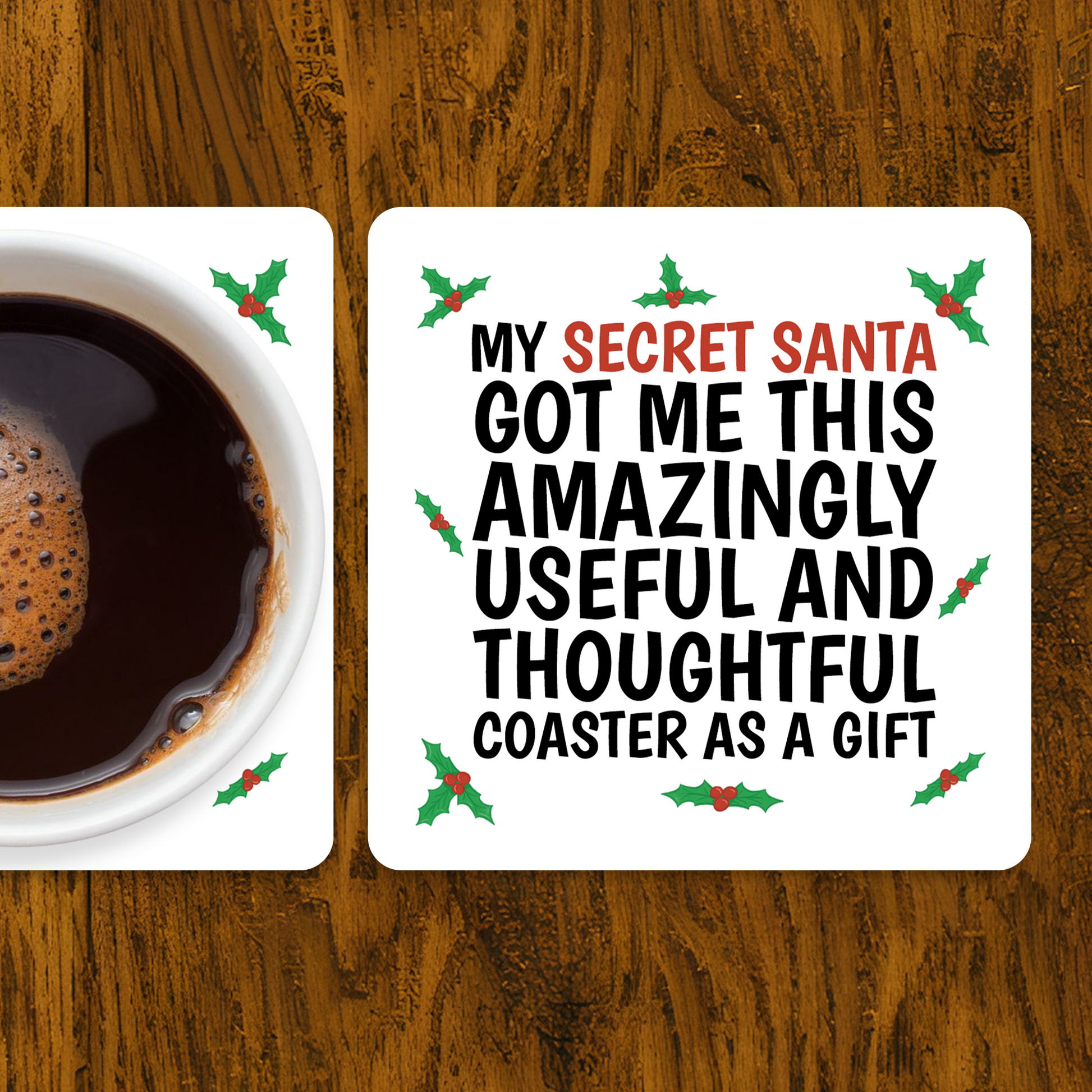 Coaster with humorous text on a wooden surface with a cup of coffee. Funny Secret Santa coaster with holly design and text “My Secret Santa got me this amazingly useful and thoughtful coaster as a gift.”