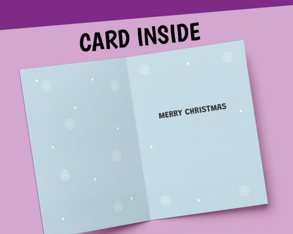 An open light blue greeting card shown against a pink background with a purple banner reading 'CARD INSIDE'. The card has white snowflake and dot patterns and the words 'MERRY CHRISTMAS' printed on the inside right panel.