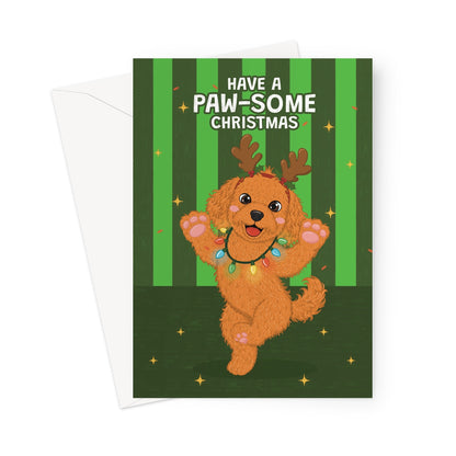 A Christmas greeting card featuring a cartoon brown dog dressed as a reindeer with the text 'HAVE A PAW-SOME CHRISTMAS' on a green striped background, shown with a white envelope behind it.